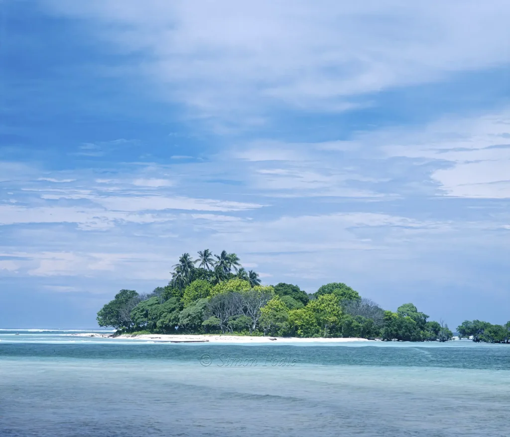 Tropical island, shallow sea bed and light clouds.