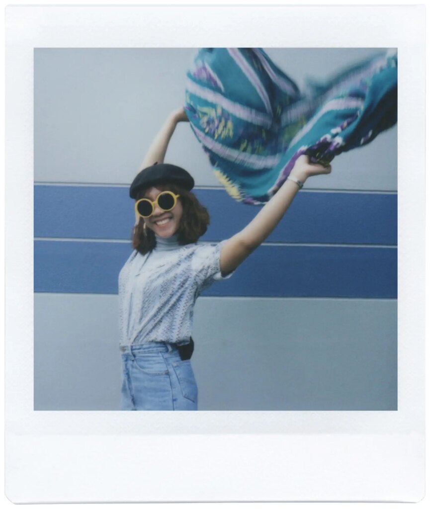 Polaroid image of person holding blue fabric over their head