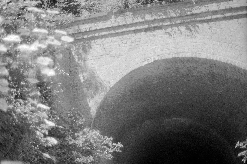 black and white photo of tunnel under railway