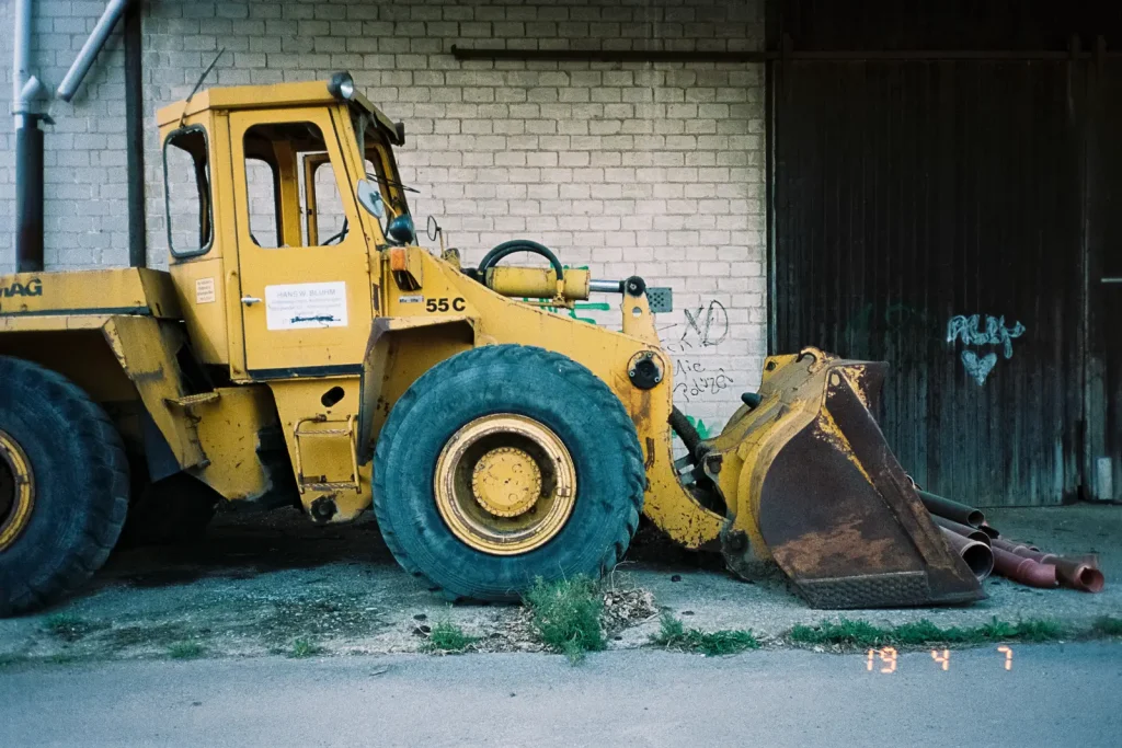 Wreck of a yellow loader standing in front of a wall