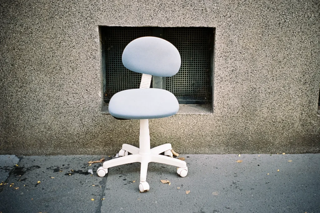 A discarded office chair standing on the pavement.