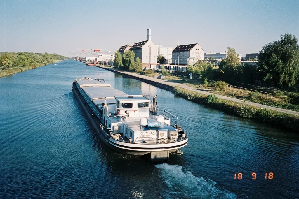 An inland vessel underway on the Mittelland Canal, captured with a Nikon L35 AD2 point-and-shoot camera.
