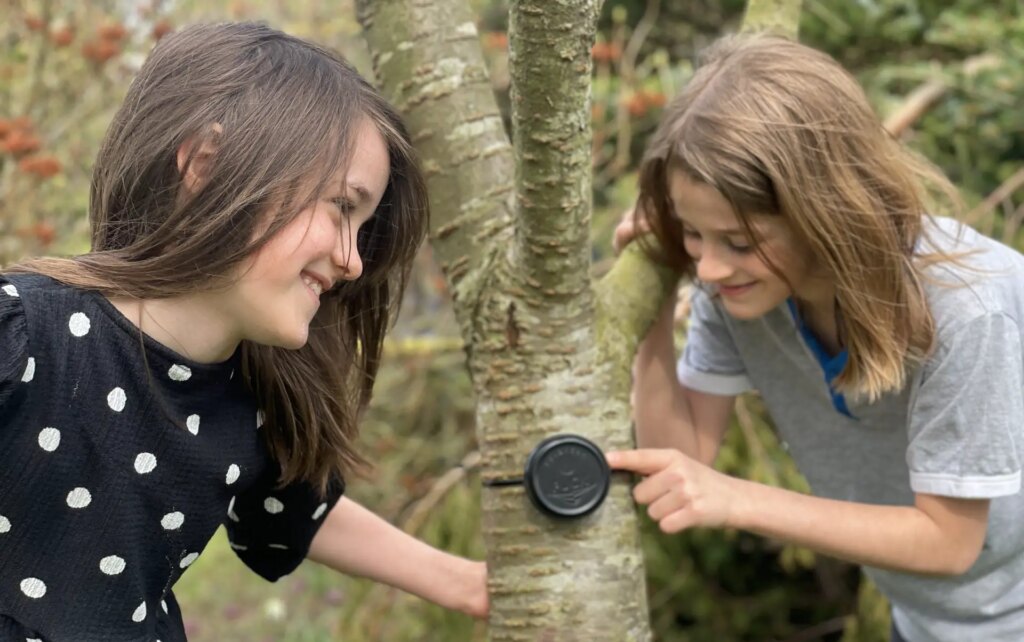 two children setting up the solarcan puck on a tree
