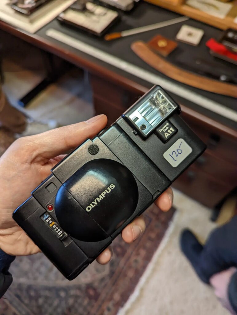 A picture of an Olympus XA 35mm film camera in my hand. Found at an estate sale.
