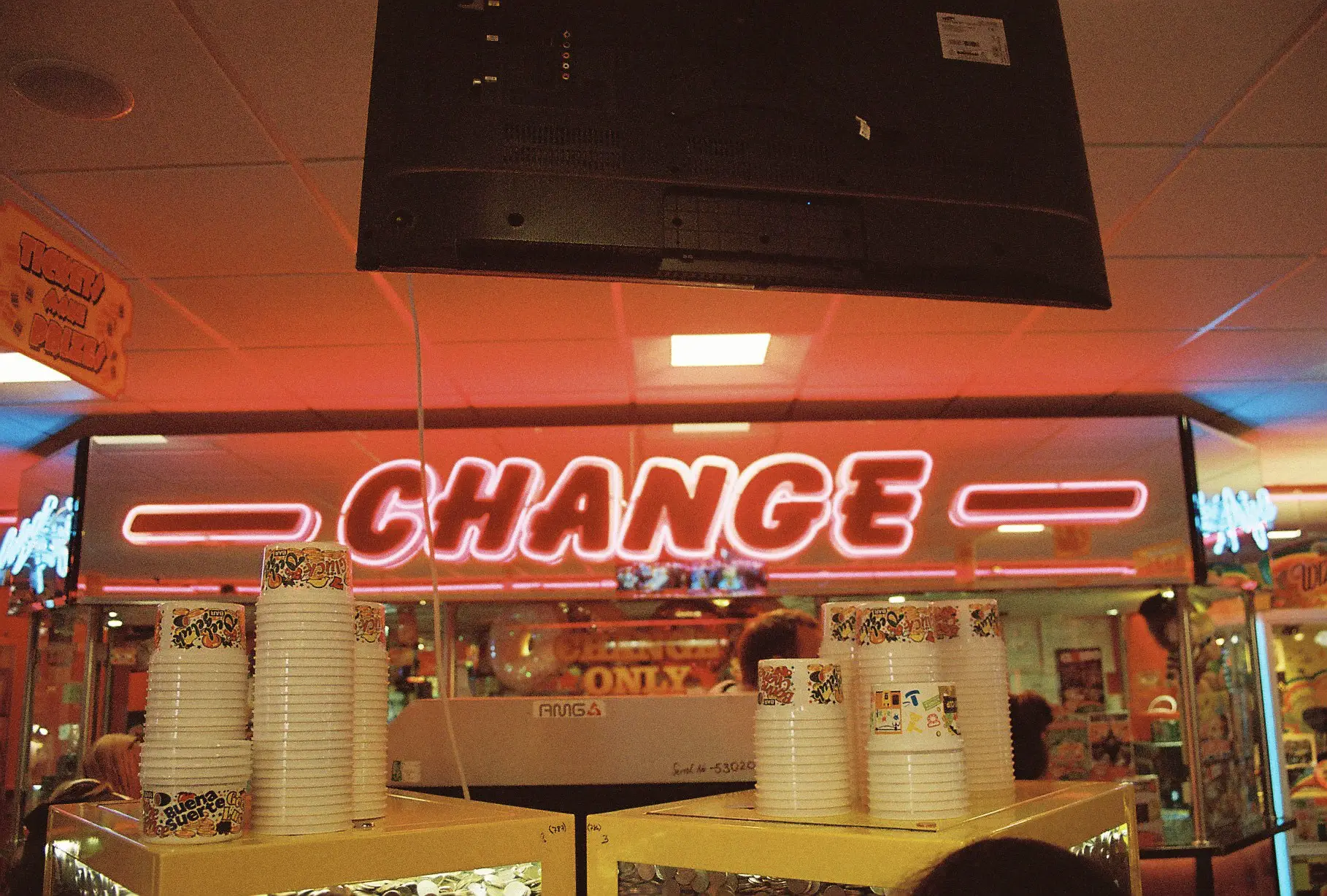 Pink tinted interior of an arcade. The word change in large neon lined letter.