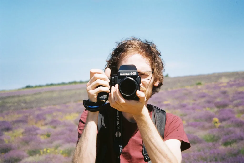Portrait of a man taking a picture with his camera. Lavender fields in the background. Taken with a Voigtländer Bessamatic using a 90 mm lens and Kodak Gold 200