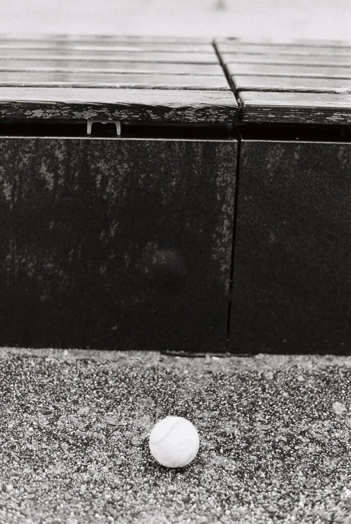 A Tennis ball laying in front of a bench