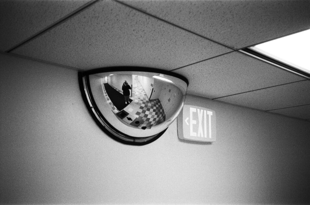 A curved mirror and exit sign on a wall
