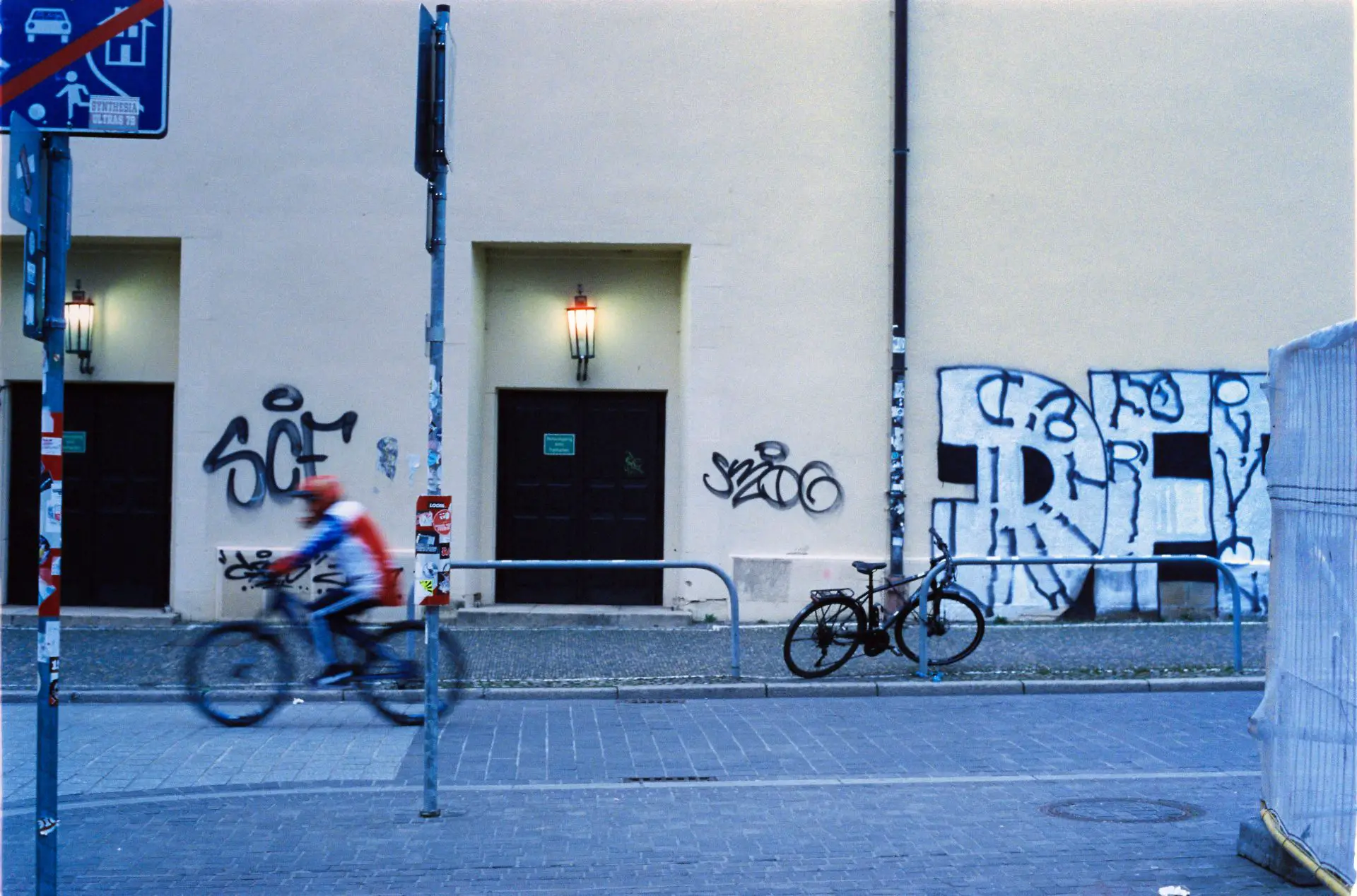 A mountain biker with a red shirt and red helmet drives thru a street