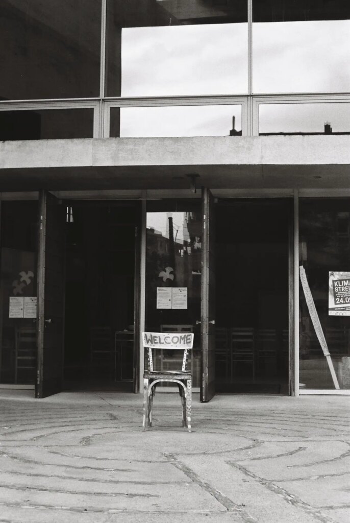 Entrance of the church. In front of it is a chair with the word "Welcome" written on it.