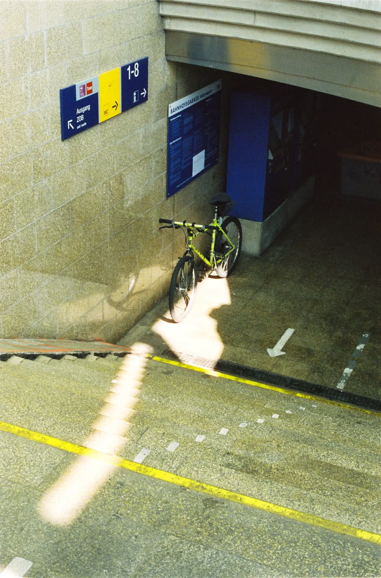 A bicycle stands at the foot of a staircase. The colours blue and yellow are prominent in this photo.