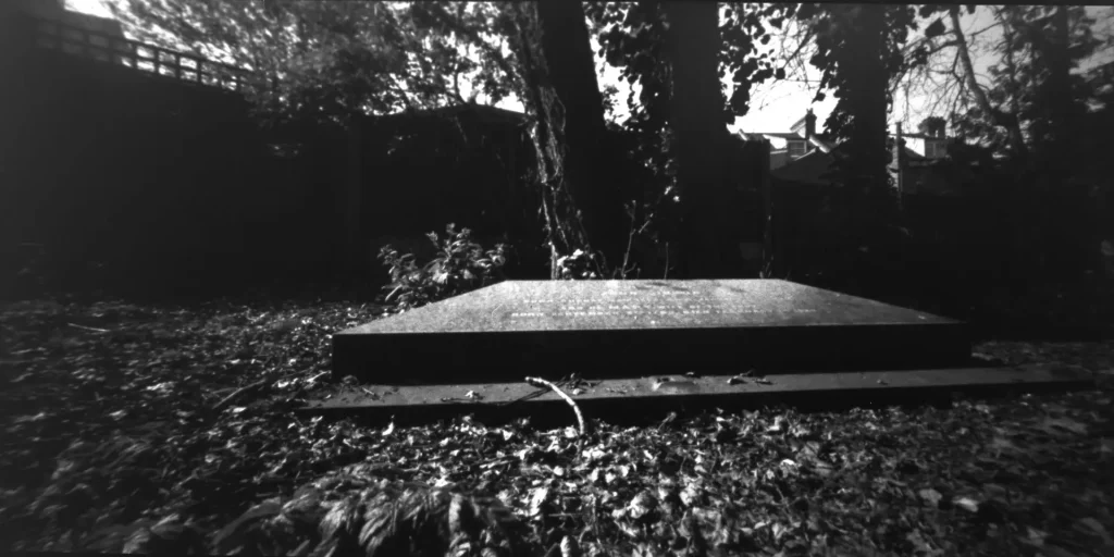 A black and white pinhole image of a gravestone with strong vignetting