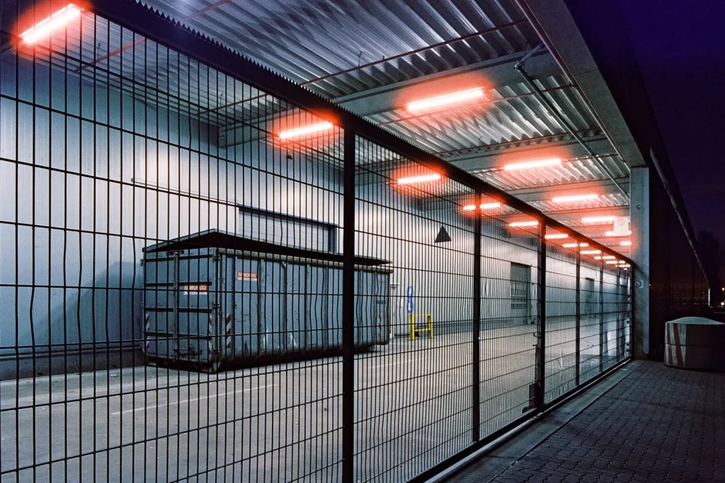 dumpster behind a lattice fence shot at night on CineStill film