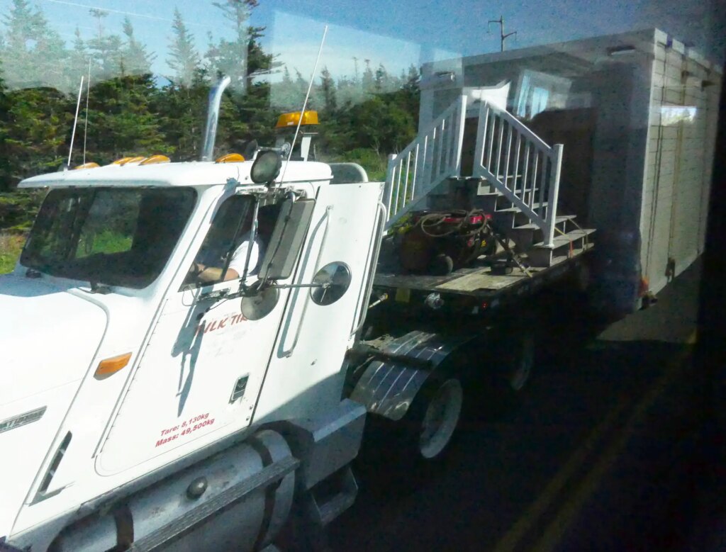 A big truck towing a tiny house with its stairs
