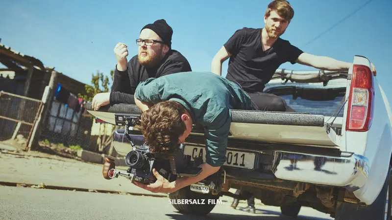 Silbersalz team in the back of a pick up truck, one member holding a camera filming off the truck