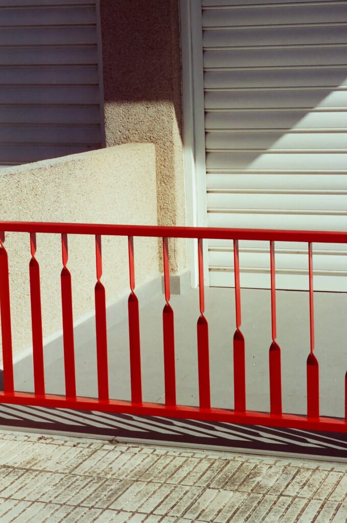 red gate in front of a building in the sun