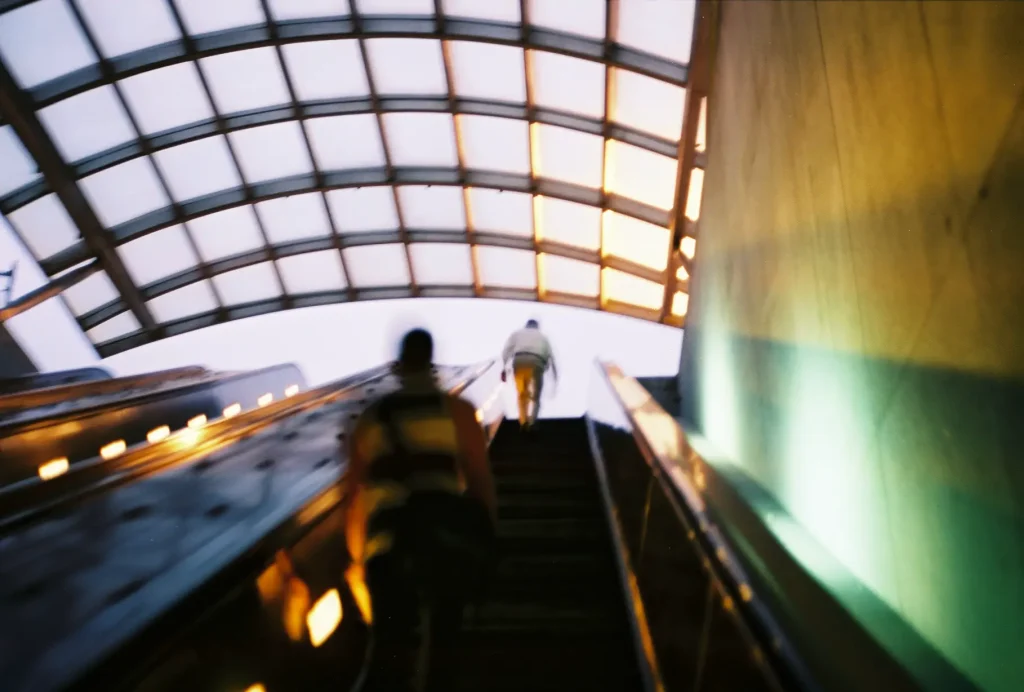 Image of commuters on an escalator upwards.