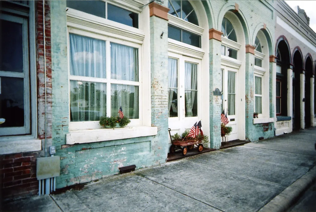 Painted blue brick buildings with windows and flags taken with a White Slim Angel ultra wide 35mm point and shoot film camera.