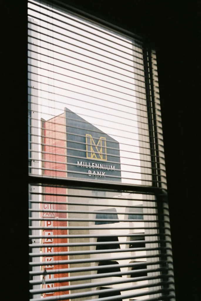 Millennium Bank building in the background behind blinds