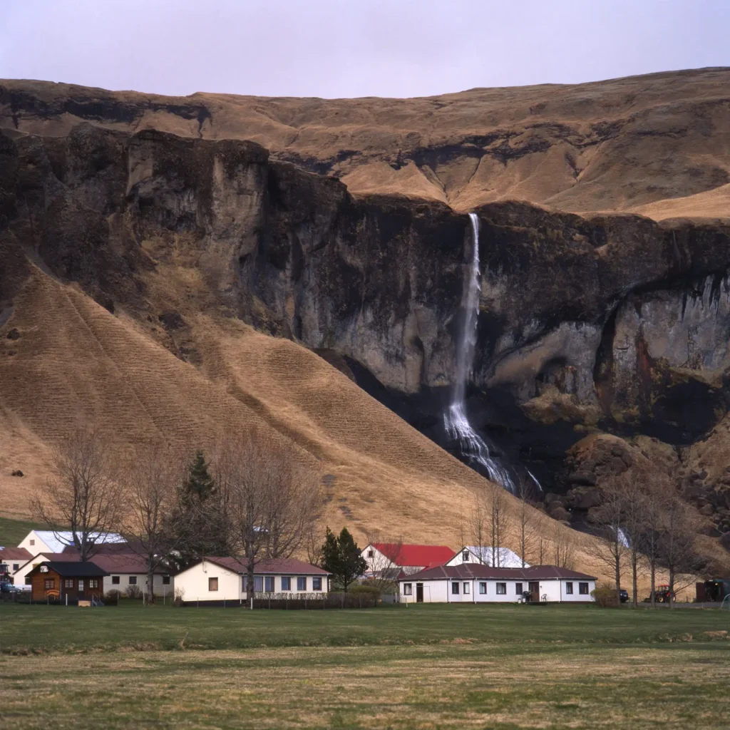 small waterfall with houses nearby 