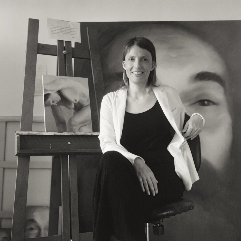 Portrait of an artist in studio with her paintings behind 