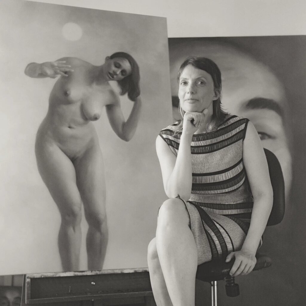 Portrait of an artist in studio with her paintings behind 