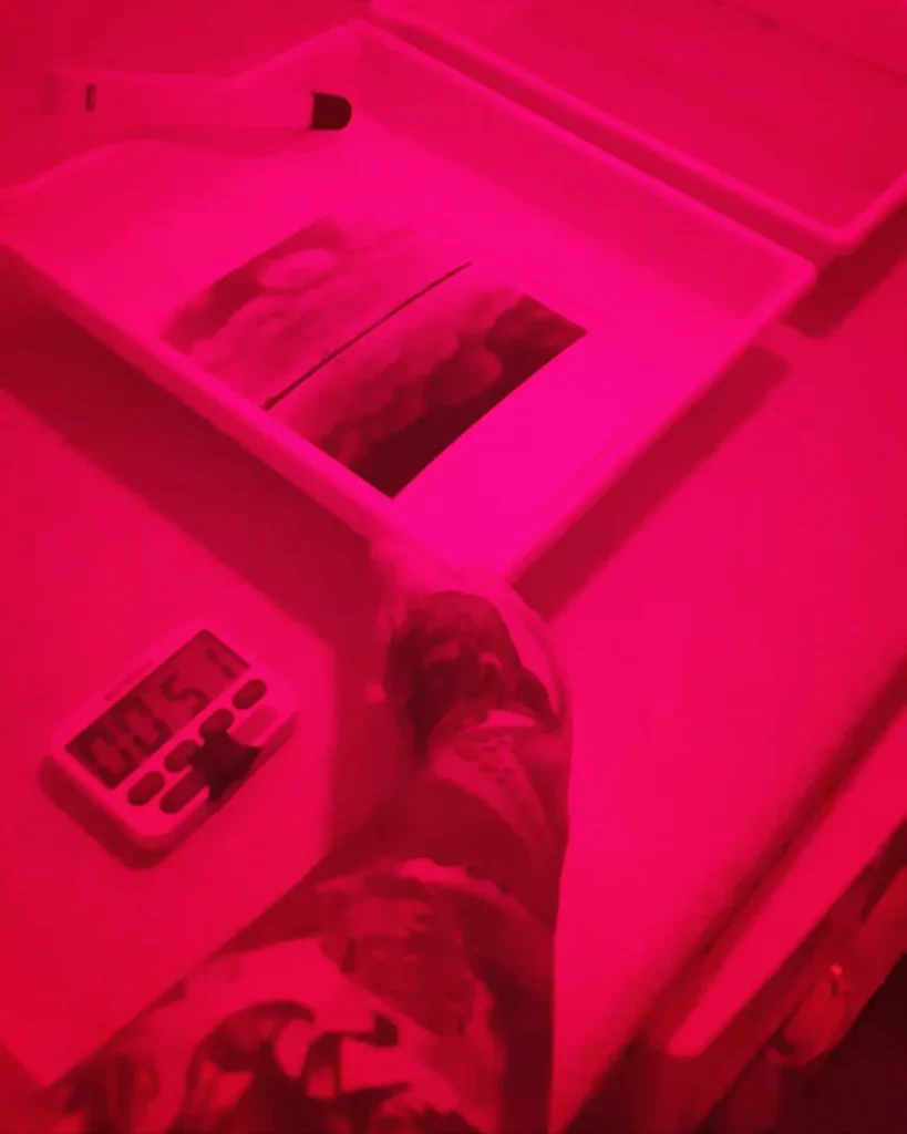 arm holding darkroom tray in red light