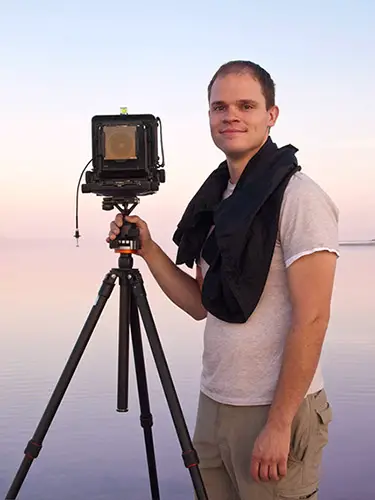 portrait of Alex Burke standing next to his large format camera