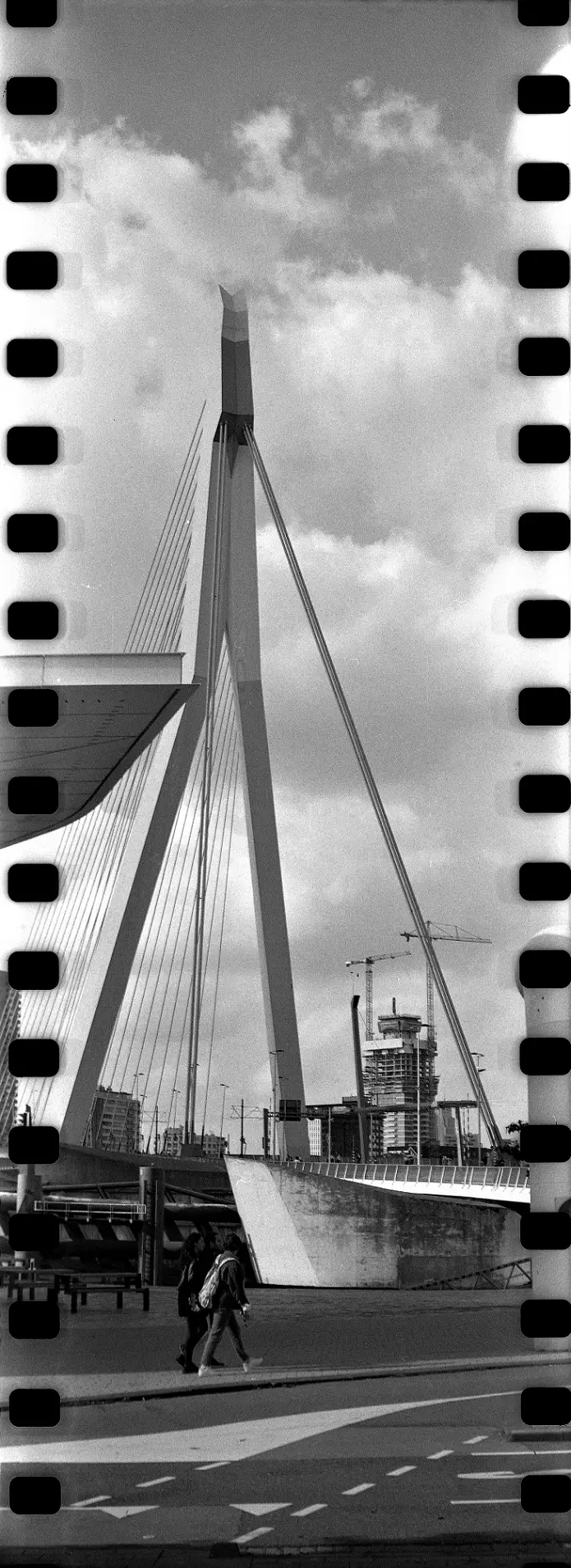 Vertical panorama showing two people in front of a suspension bridge