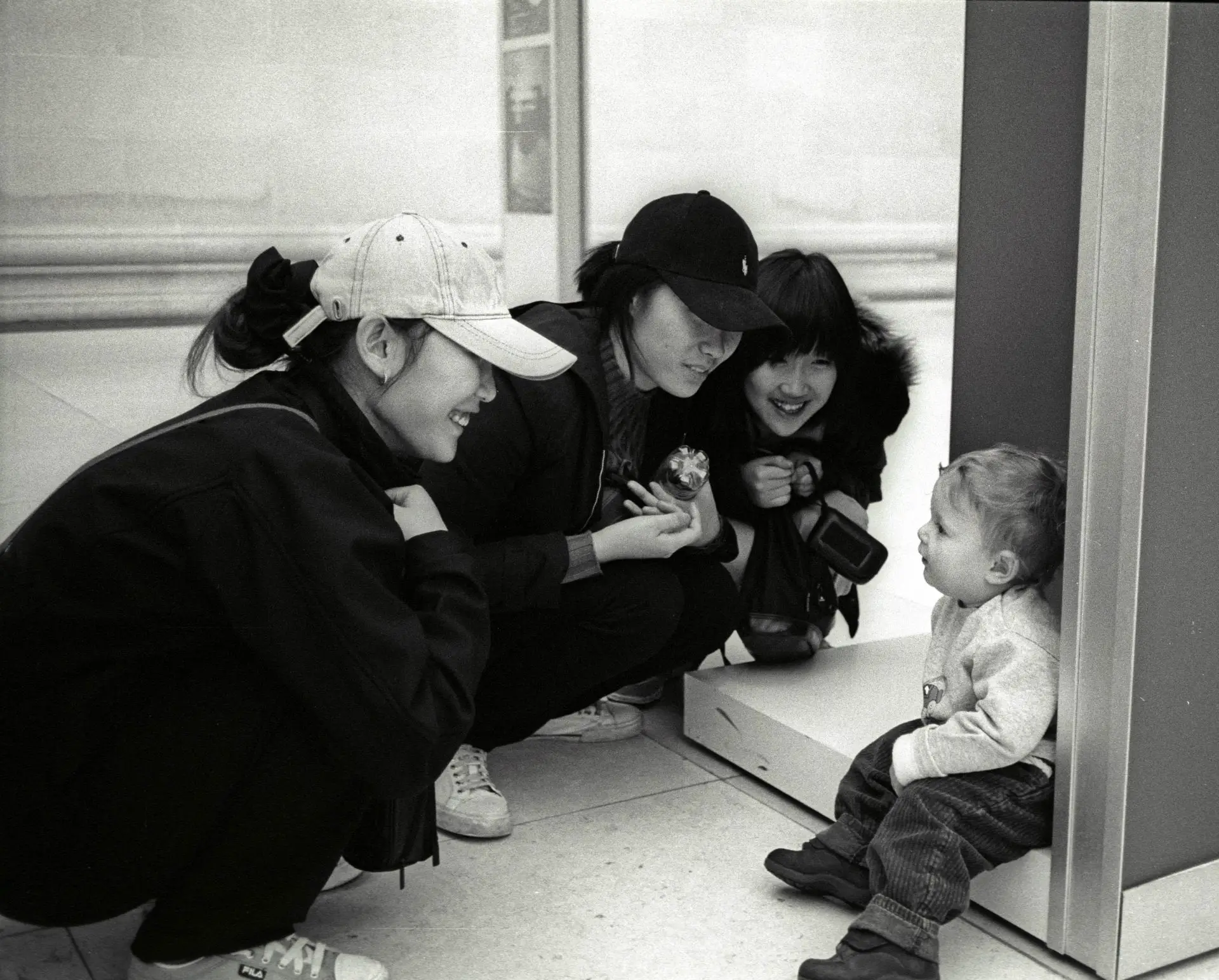 women crouching down looking at toddler