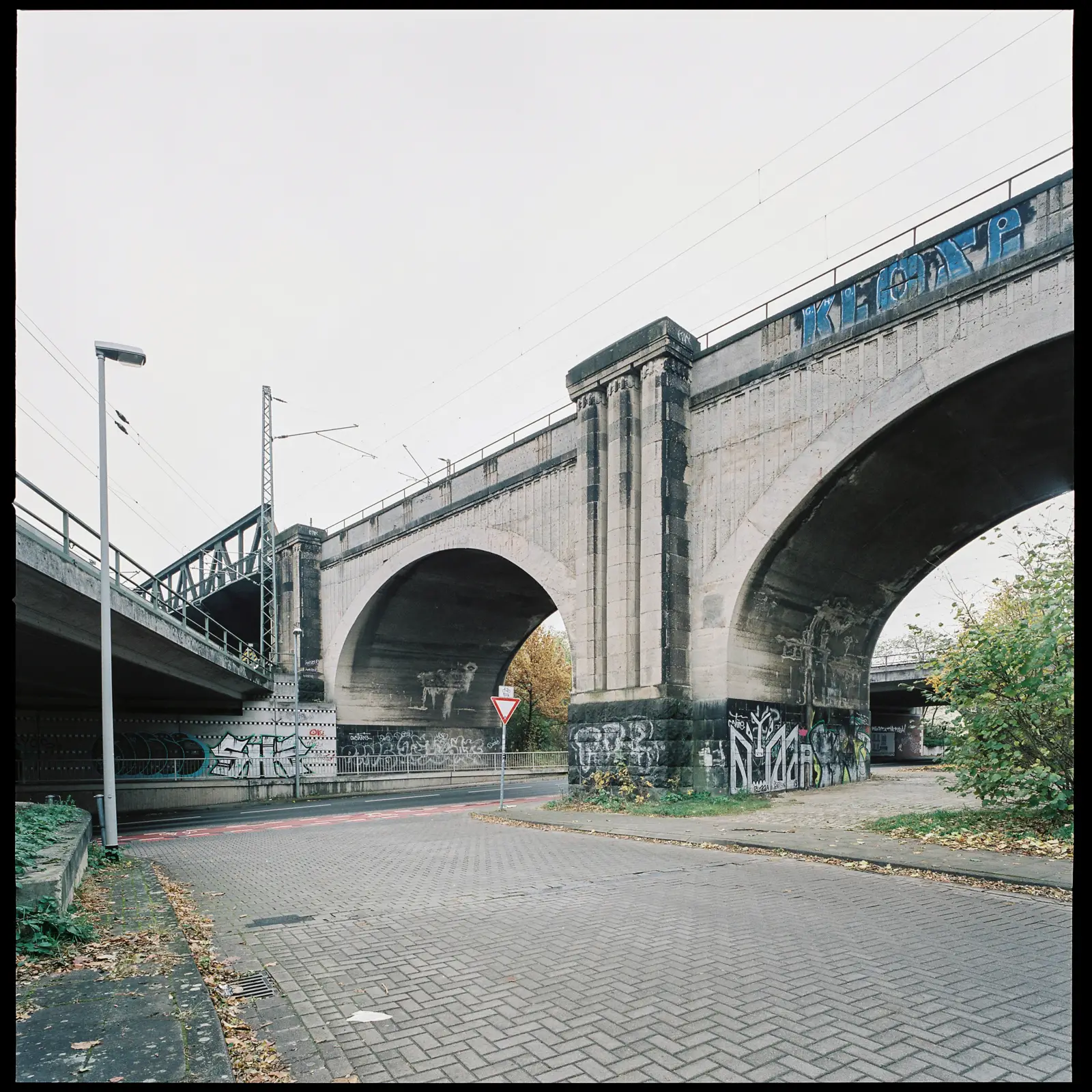 6x6 photograph of a monumental railroad bridge; the bridge's concrete appears quite run-down