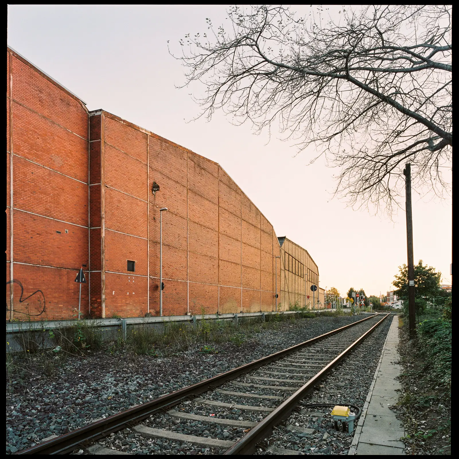railroad tracks running along a large windowless factory building