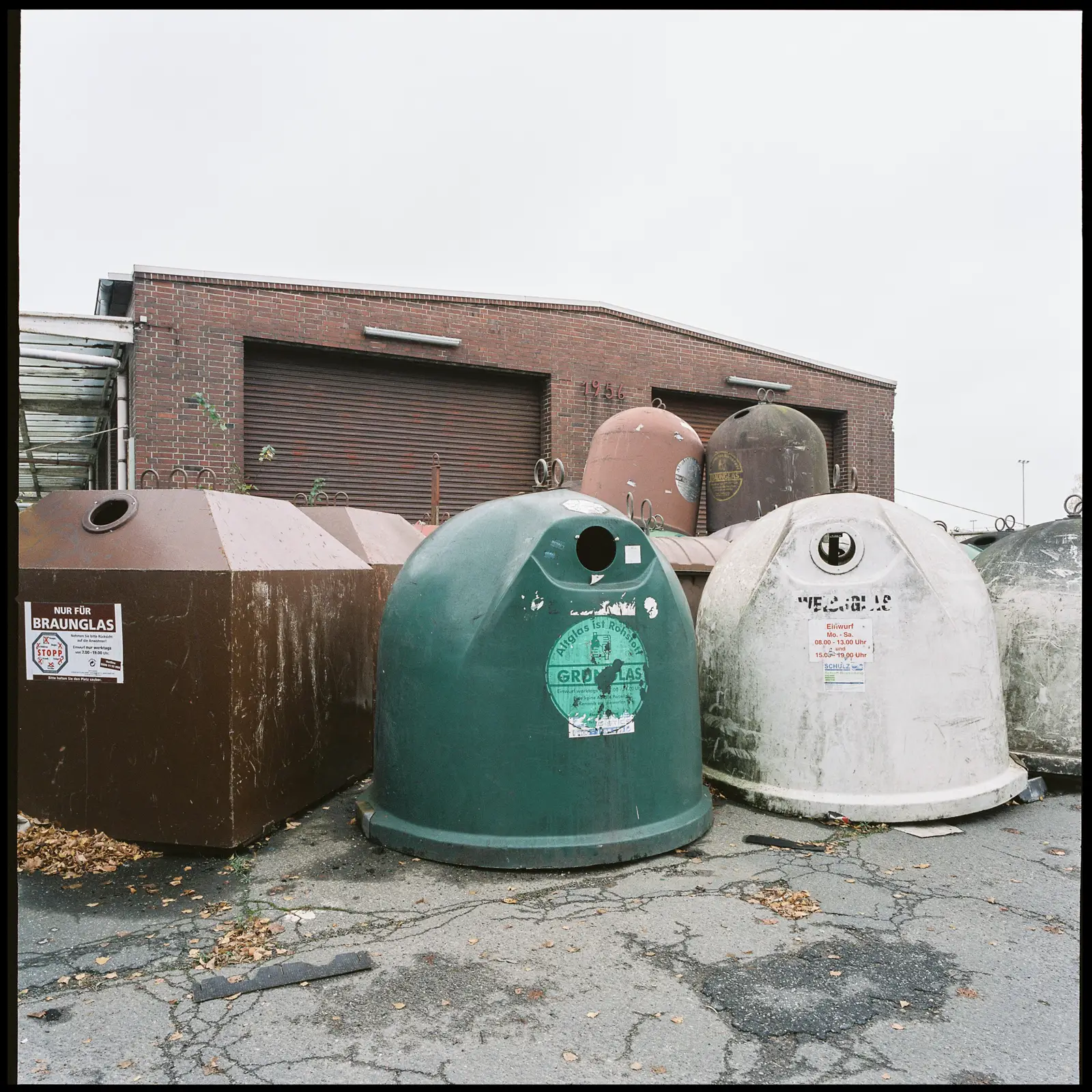 shabby corner at Nordhafen inland harbor: several disused bottle bank stand in front of a small warehouse