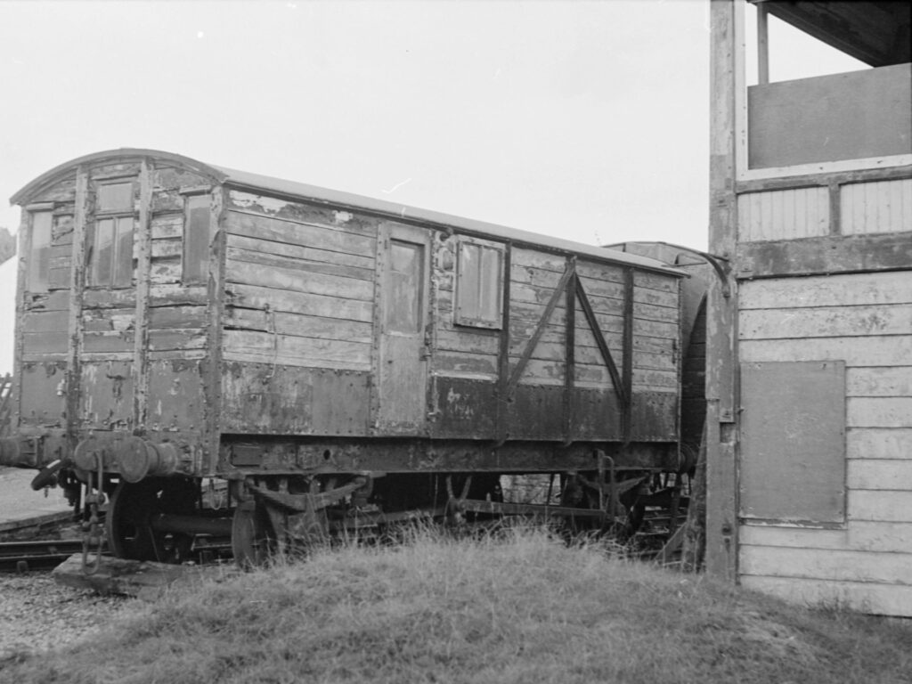 An old train cargo carriage next to an old train station tower