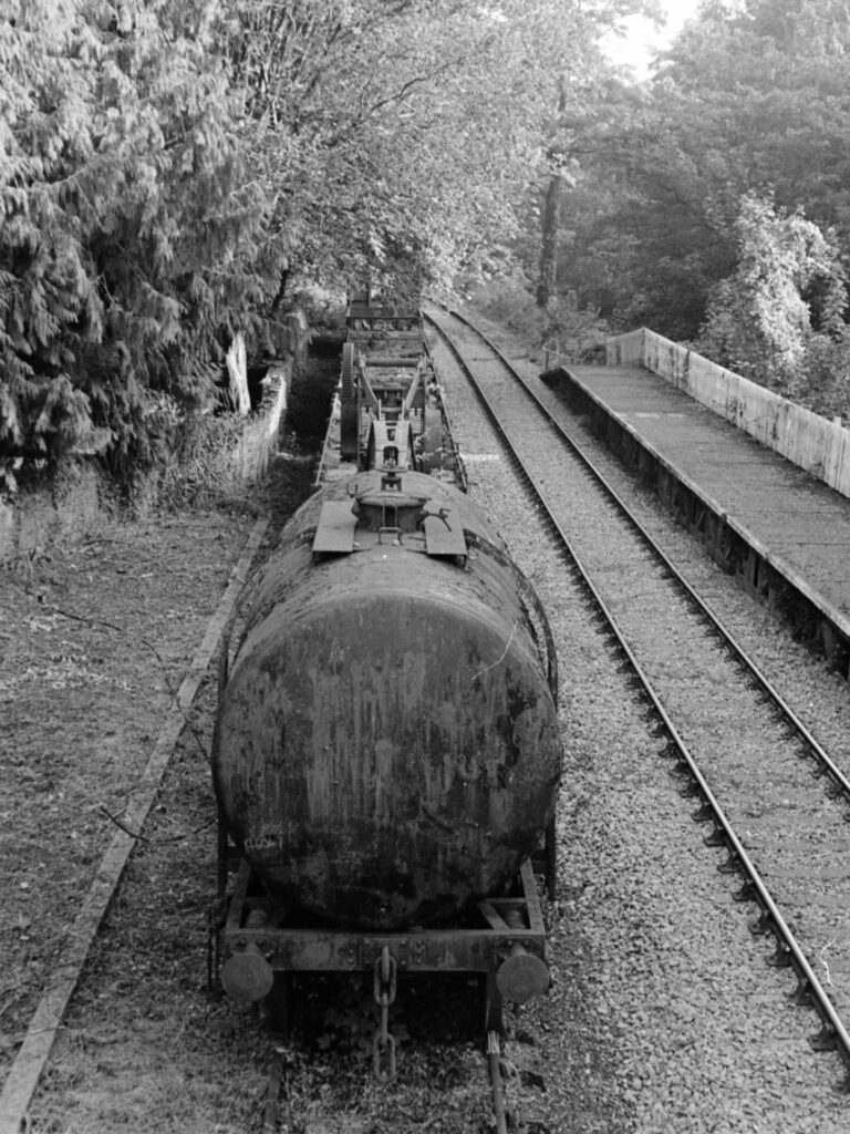 Head on view of an old rusty cylindrical container train carriage on tracks,