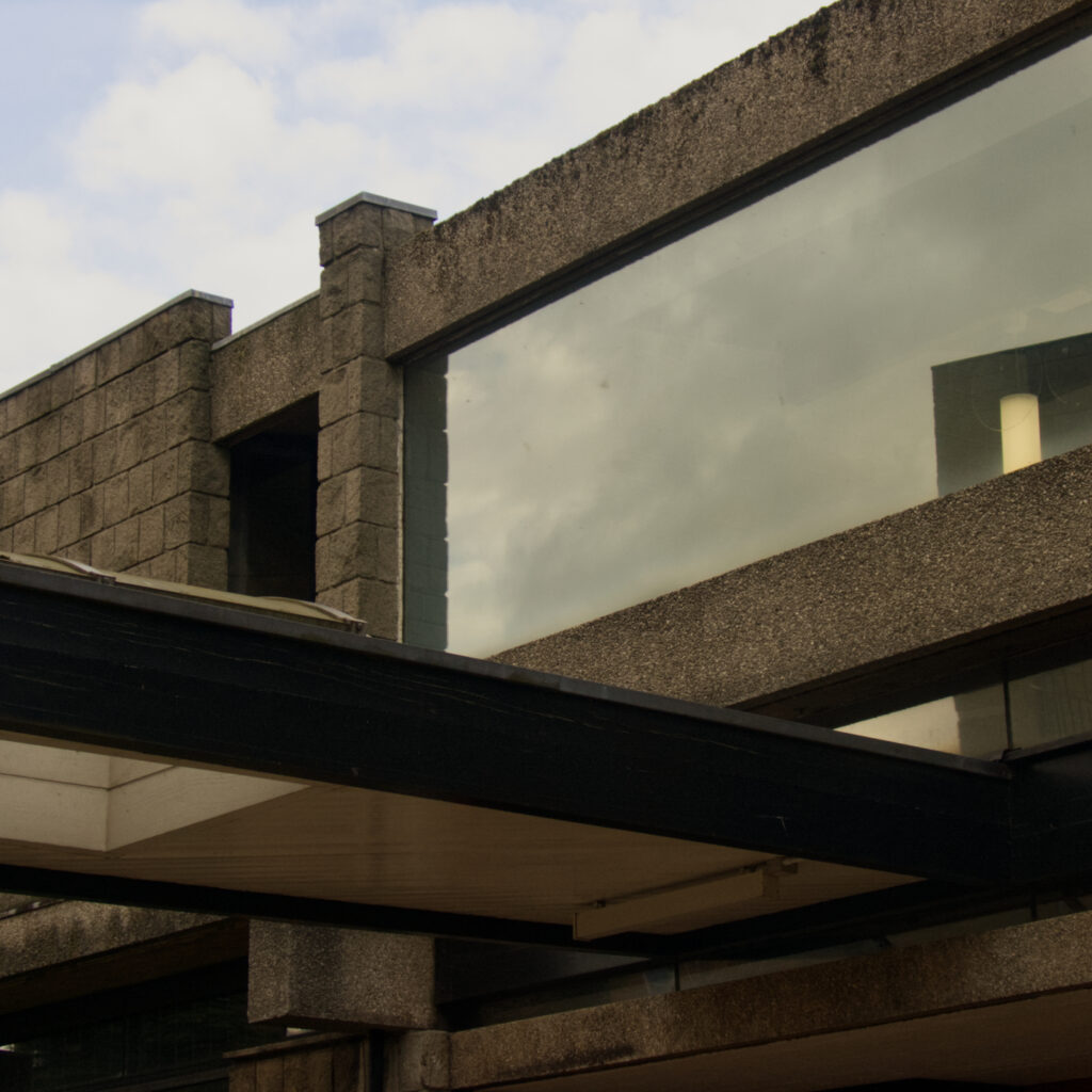 Photograph of Brutalist Architecture and a reflection in a widow emphasizing geometric shapes 
