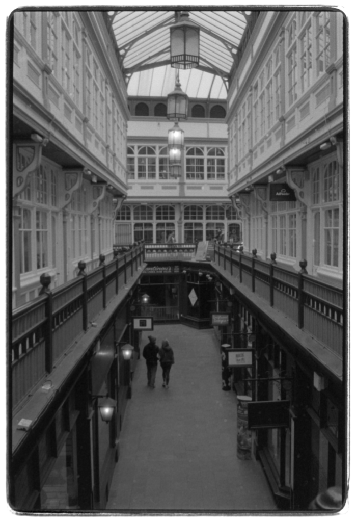 Two people strolling down an old arcade.