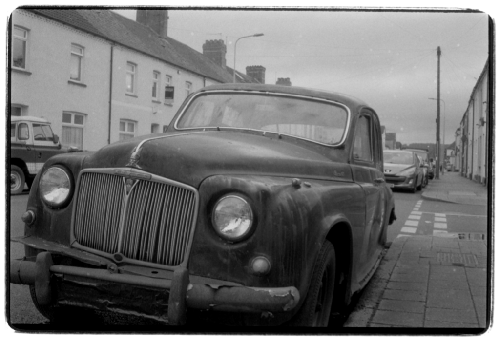 A run-down classic car on a suburban street.