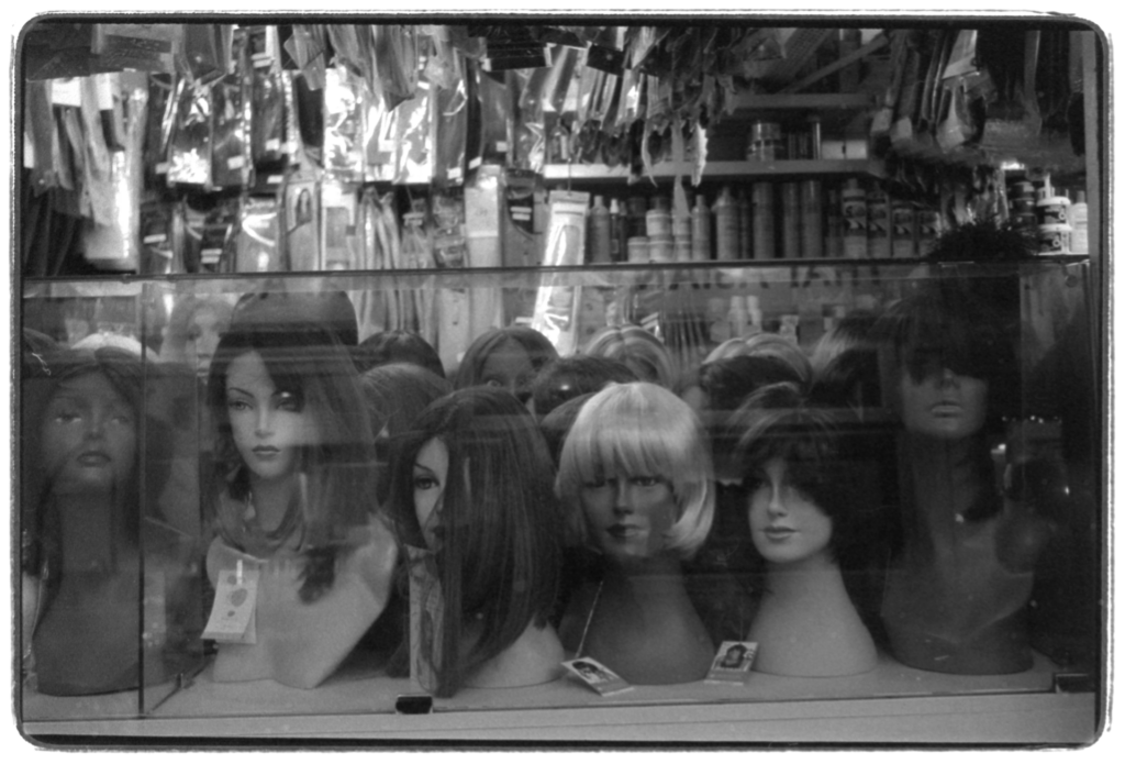 A market stall with a number of wigs displayed on mannequin heads.