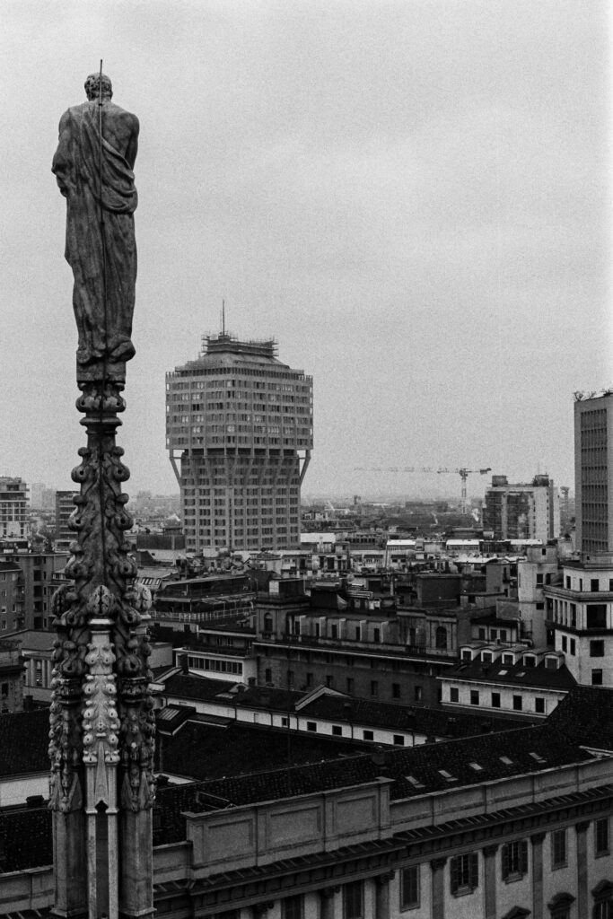 An ornate pinnacle of the Duomo with the Torre Velasca in the background