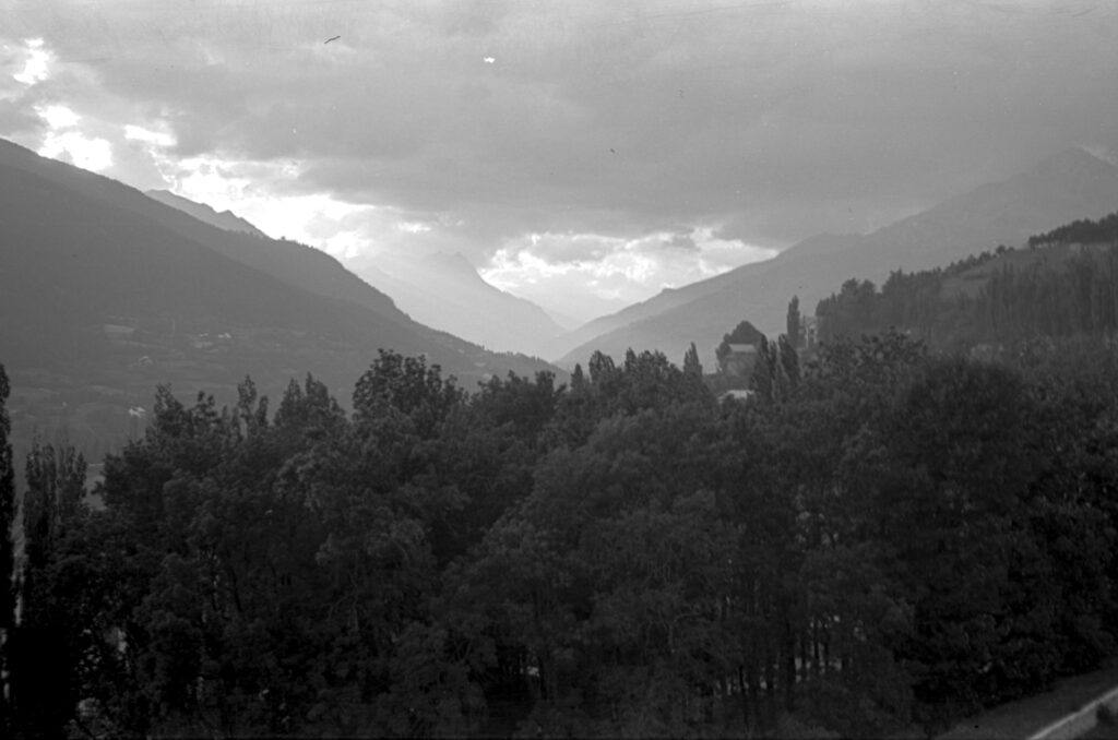 Black and white image of rain clouds in a valley in the alps.