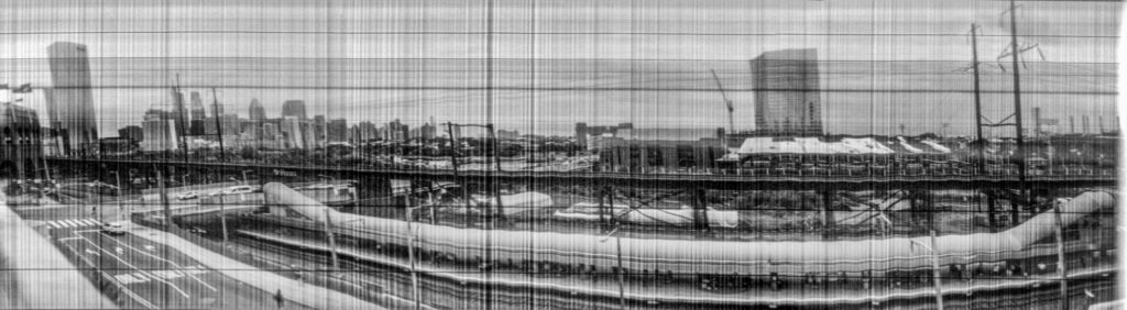 Another wide panoramic image in black and white. A city is visible in the distance but there is still signifiant black and white vertical banding. 