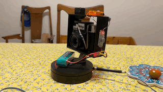 An animated gif showing the camera system turning on the turntable while the servo in the frame spins the film advance. 