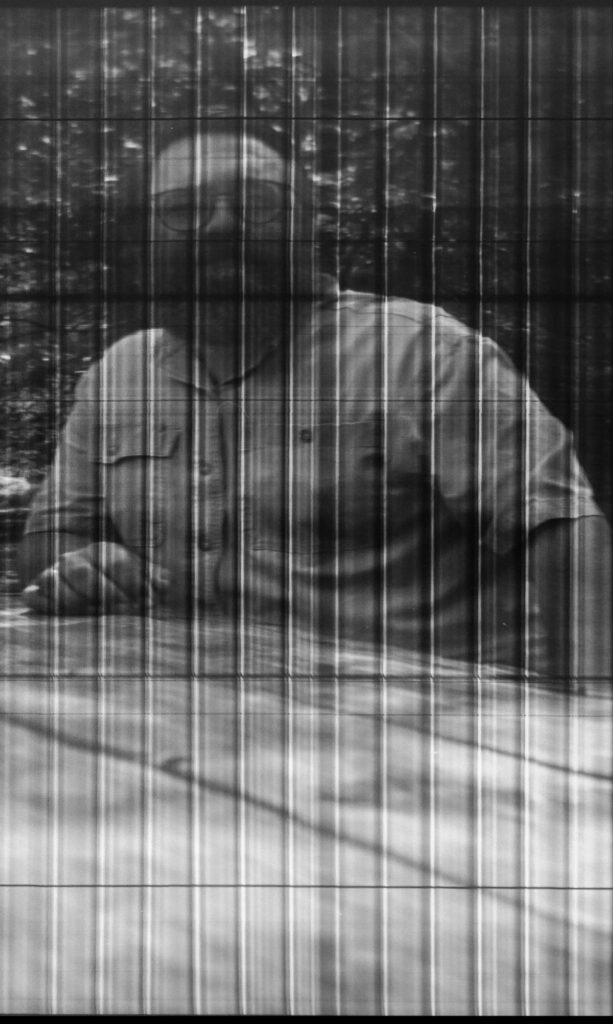 A crop from the previous image showing the author sitting at a picnic table in the middle of the panorama. The person is clearly visible, but the banding is more visible in this zoomed in view. 