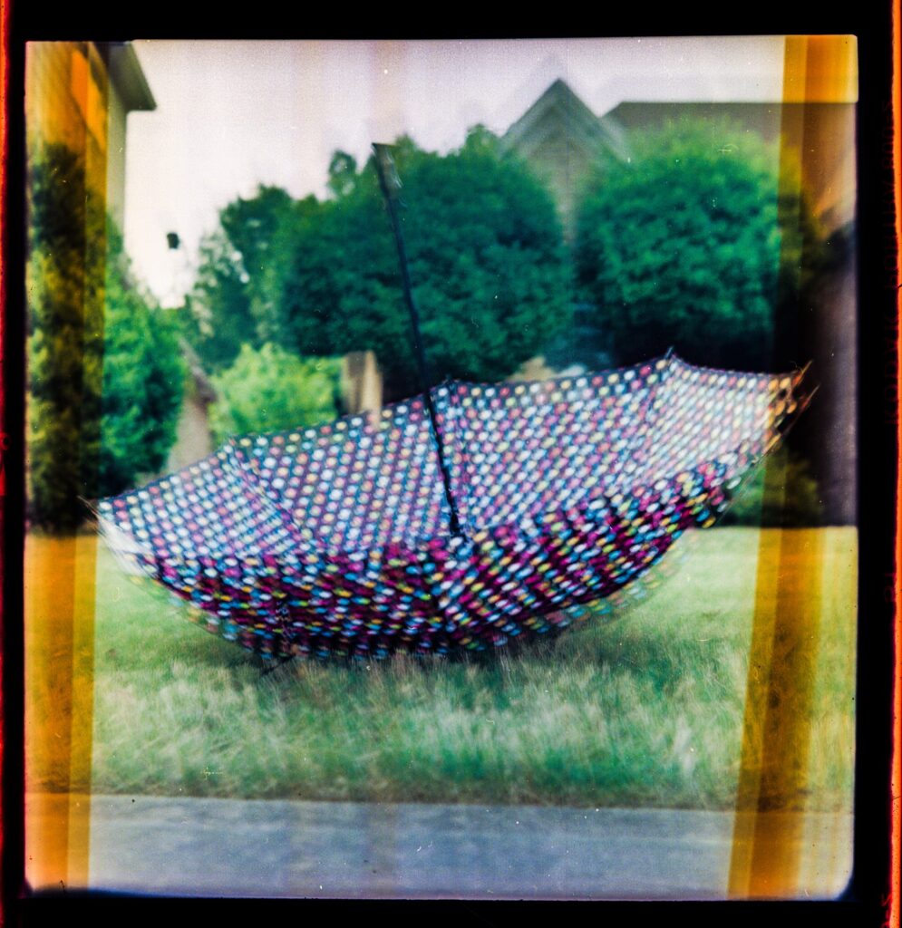 An out of focus, blurry, and distorted photo of an umbrella with colorful dots