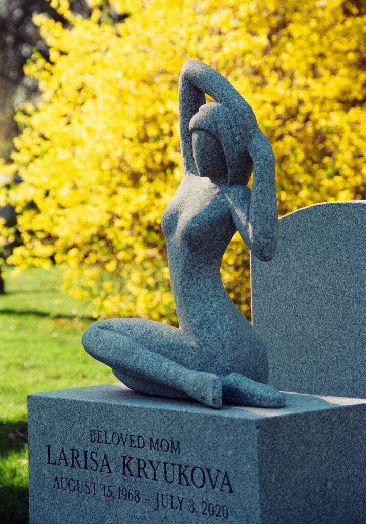 Monument at a cemetery with blooming forsythias in the background