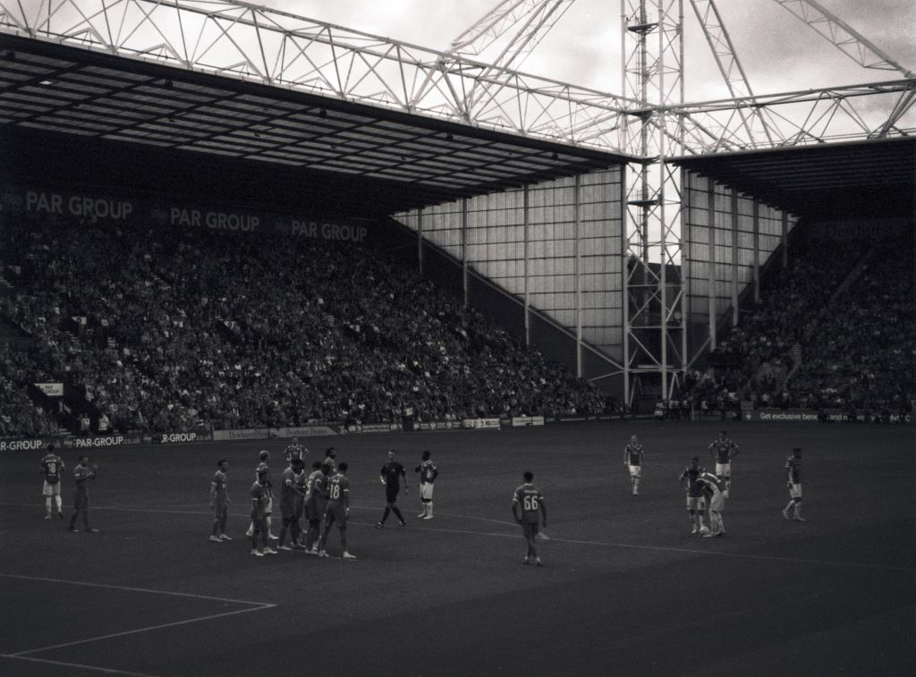 Liverpool FC playing at Deepdale - a wide shot shows the stadium looking dramatic in black and white. In the foreground we can see Trent Alexander-Arnold.