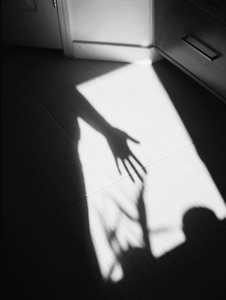 Shadow of a hand off a tiled floor.