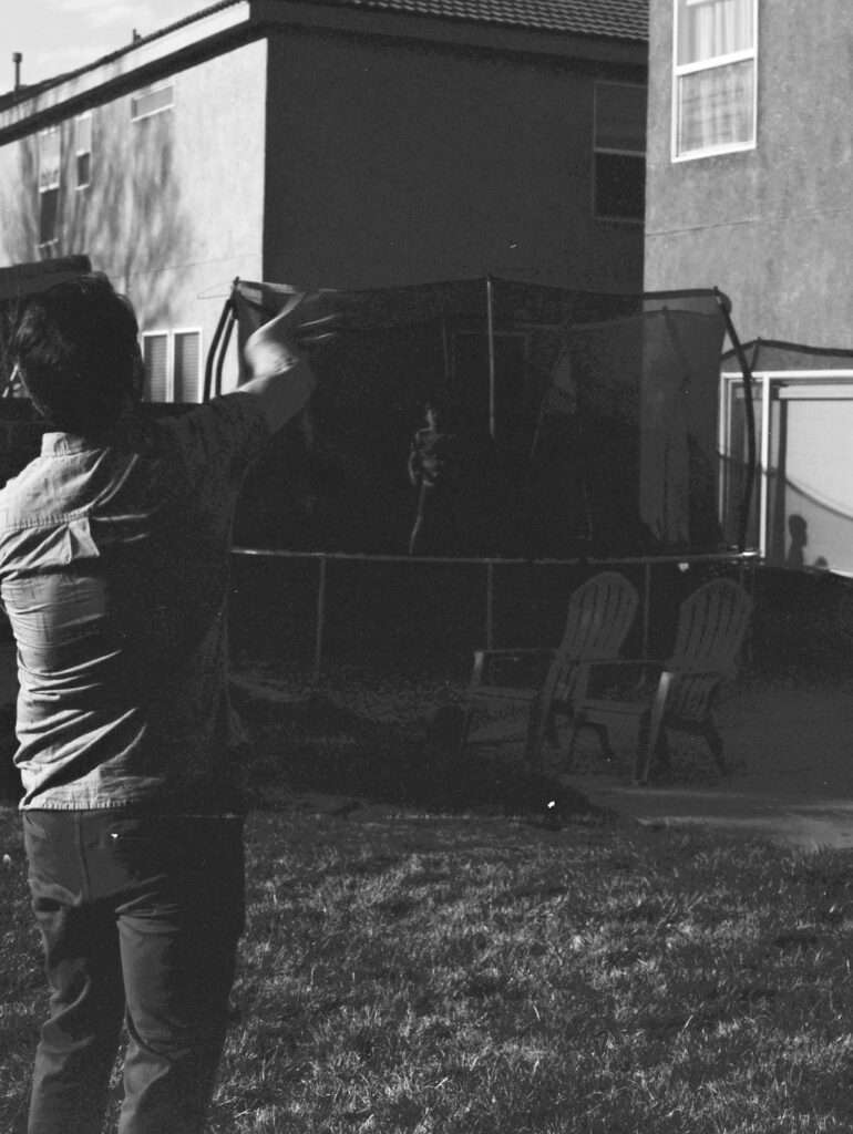 Father a son playing catch while jumping on a trampoline.