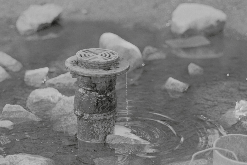 Drainpipe in a pool of water, surrounded by rocks.